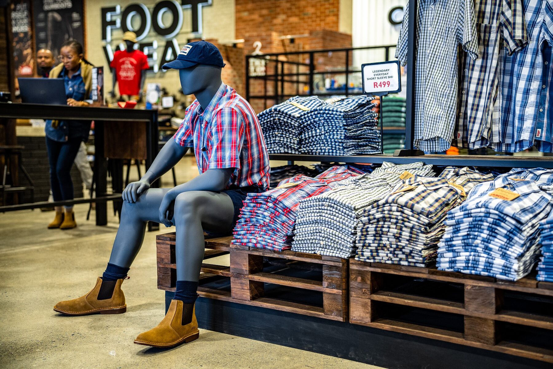 A seated male mannequin presenting workwear beside a folded shirt display
